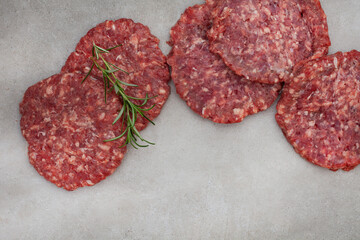 Raw free range 100% beef burger patties on mottled grey with copy space