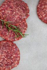 Raw free range 100% beef burger patties on mottled grey with copy space