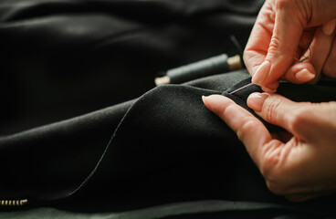 Hands of tailor finishing tailored suit