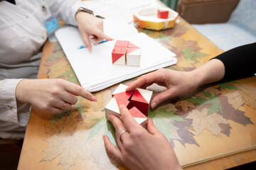 The hands of a psychologist doctor and the patient's hands. Psychologist conducts a test with cubes.The psychologist identifies problems.