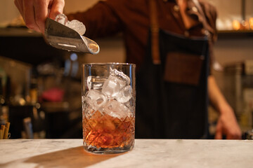 copo de Negroni sendo feito por barman.