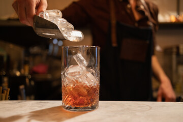 copo de Negroni sendo feito por barman.