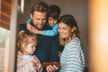 Happy man sharing smart phone with family seen through window