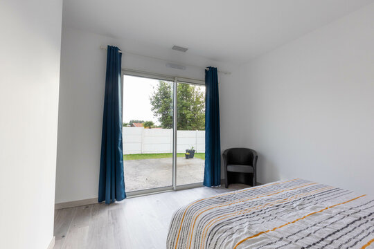 Int&eacute;rieur d'une chambre dans une maison neuve, la chambre comporte une baie vitr&eacute;e et des rideaux