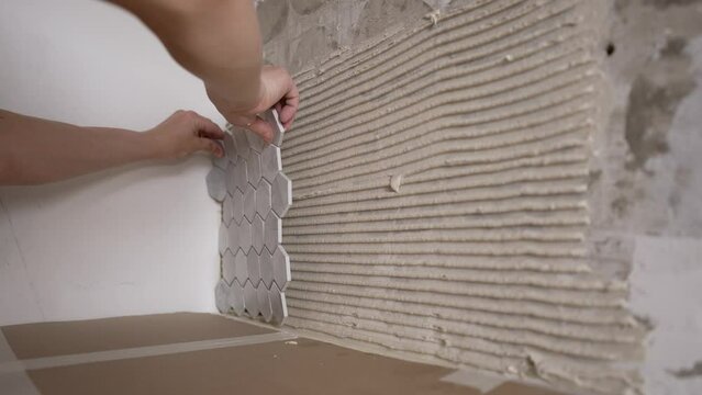 The master glues mosaic ceramic tiles on the wall. Laying mosaic tiles by the hands of a master. Mosaic tile gluing.
