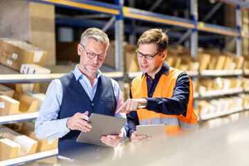 Worker pointing on tablet PC discussing with manager in warehouse