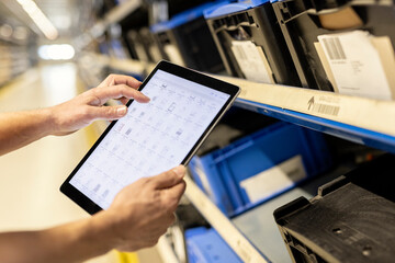 Hands of worker using tablet PC for checking inventory in warehouse