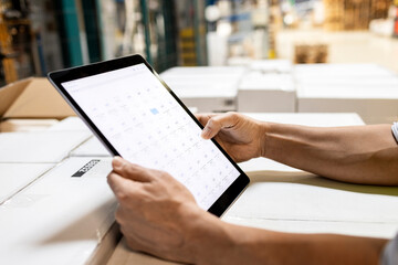 Hands of worker checking inventory on tablet PC in warehouse