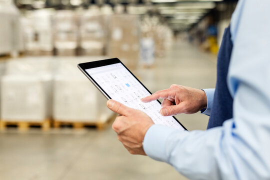 Hands of manager checking list through tablet PC in warehouse