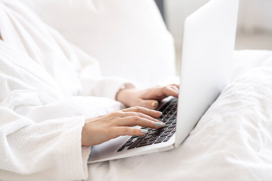 Woman using laptop sitting on bed at home