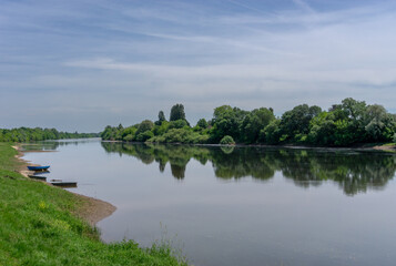 landscape reflections in the calm Dordogne River with colorful wooden rowboats on the river bank