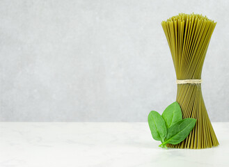 green spaghetti in a bunch with spinach on gray background. copy space
