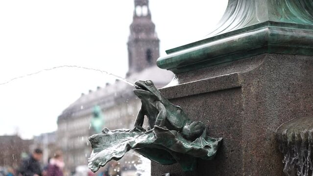 Frog design Stork fountain in Copenhagen central square Denmark with tourist and tower slowmotion