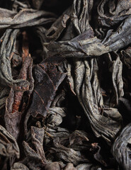 Dried black tea leaves as background.