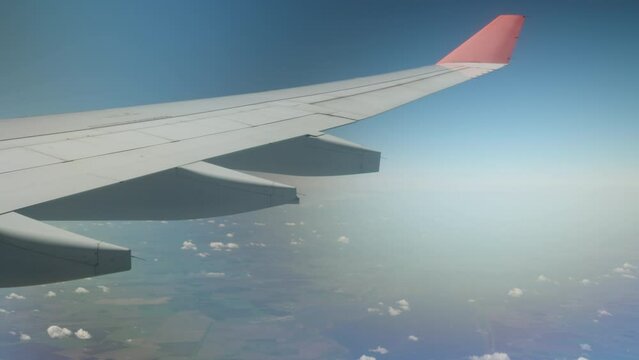 Airplane wing in the clouds. Flying over sea and land
