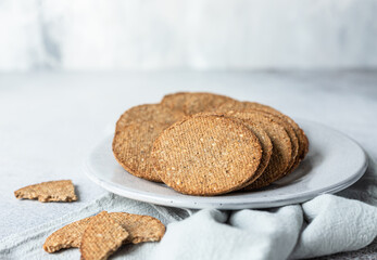 Plate with tasty crackers with sesame and flax seeds on grey background.