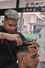 Young handsome man in barbershop having a haircut