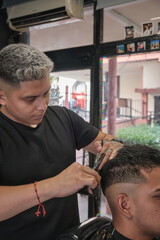 Young handsome man in barbershop having a haircut