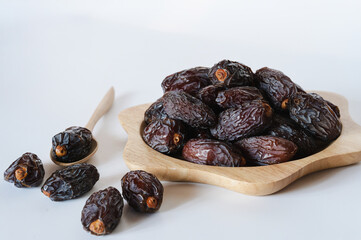 Medjool dates in a wooden container on a white background. It is a fruit that Muslims eat during the fasting month.