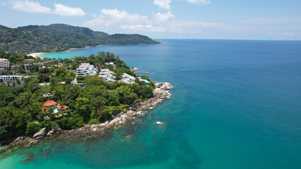 Clear water with a rocky Kata beach. The bottom is visible. Aerial view of the ocean and shore from the drone. The whole island is green. There are beautiful hotels. A tourist place in Thailand