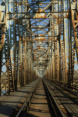 central shot of one way track on an old rusty train bridge