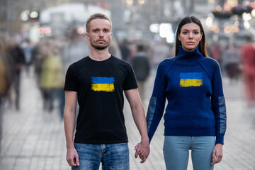 The young man and woman stand in the middle of the street and hold hands.