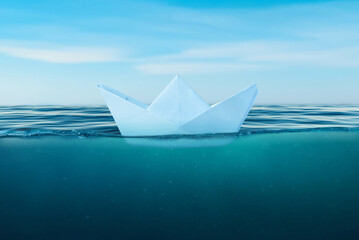 Paper boat on the sea surface. View under the sea. The concept of courage and bravery in life and the risk of making bad decisions that can sink a ship - obrazy, fototapety, plakaty