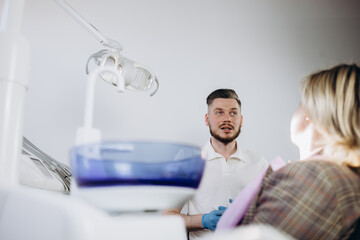 Fototapeta premium Girl patient goes to the dentist with a toothache in the dental office. Young woman holding the hand of a sick tooth