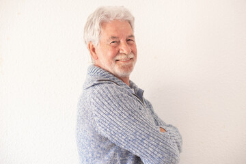 Portrait of handsome bearded senior man in casual clothes with crossed arms smiling and looking at the camera while standing on white background