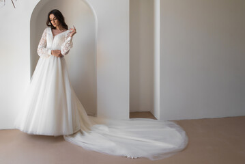 Fototapeta na wymiar Beautiful bride in a luxurious wedding dress on white background
