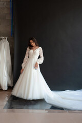 Fototapeta na wymiar Full length bride portrait. Elegant woman in white wedding dress spinning in beige interior.