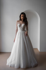 Fototapeta premium Beautiful bride in a magnificent white wedding dress of tulle with corset lacing and long beauty hair