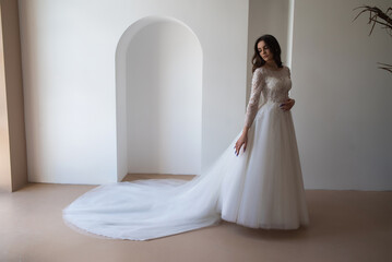 Full length portrait of young beautiful woman wearing white wedding dress. Elegant bride standing and posing