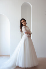 Fototapeta premium Full length portrait of young beautiful woman wearing white wedding dress. Elegant bride standing and posing