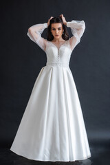 Fototapeta premium Beauty Portrait of bride wearing in wedding dress with voluminous skirt, studio photo. Young attractive bride. Smiling beautiful young bride