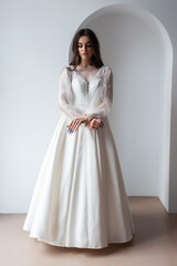 Fototapeta premium Beauty Portrait of bride wearing in wedding dress with voluminous skirt, studio photo. Young attractive bride. Smiling beautiful young bride