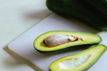 Avocado on an white wooden table, half on a fruit bowl, healthy food ideas still life.