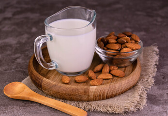 Almond milk in an almond decanter on a wooden tray.
