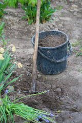 A hoe slipped over a black bucket of native soil