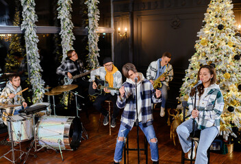 Young rock band sings and plays on the background of the Christmas tree New Year's songs