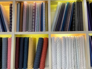 A collection of colorful fabrics with various motifs in the wardrobe. A clothing store wardrobe with multi-storey shelves looks luxurious with a design like a minimalist home interior.