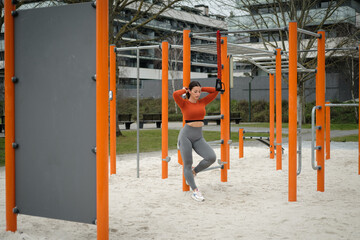 Young woman geting ready for fitness and strength suspension training at urban park.