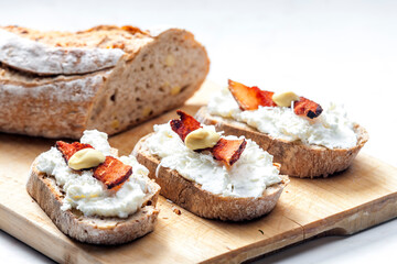 garlic spread on slice of bread served with bacon, grated cheese and mustard