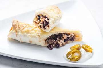 beef burrito with rice and beans served with whipped cream and jalapenos
