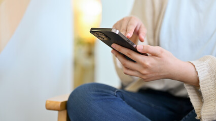 Woman taking a break in her living room, using smartphone.