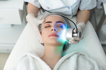 Ultrasonic massager. Light skin treatment, the woman in the beauty salon