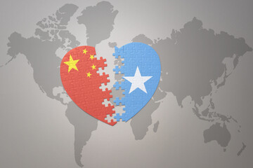 puzzle heart with the national flag of china and somalia on a world map background. Concept.