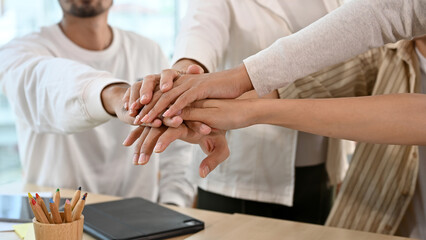 Diverse businesspeople put their hands on top of each other together.