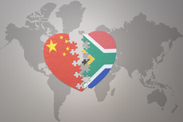 puzzle heart with the national flag of china and south africa on a world map background. Concept.