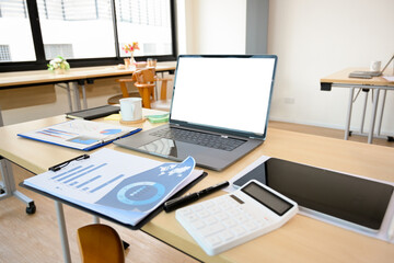 Modern office desk with open laptop computer, report, calculator and supplies.